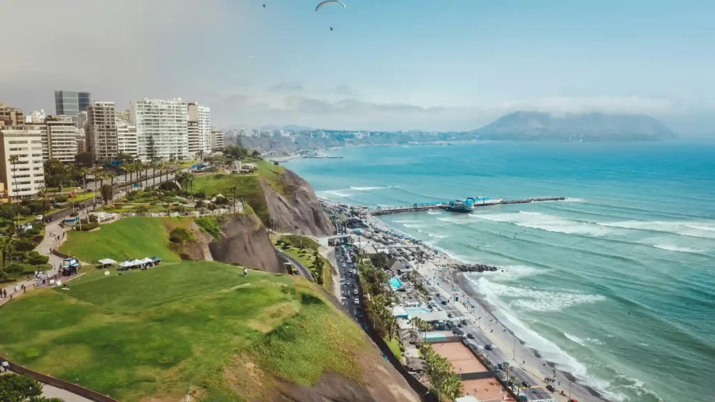 Vista de los acantilados de la Costa Verde y el malecón de Miraflores en Lima, con parapentes sobre el Océano Pacífico.