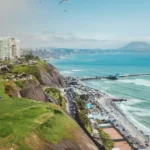Vista de los acantilados de la Costa Verde y el malecón de Miraflores en Lima, con parapentes sobre el Océano Pacífico.