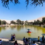 Espejo de agua esmeralda del Oasis de la Huacachina bajo las imponentes dunas de arena