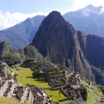 Vista amplia de las terrazas, recintos y la montaña Huayna Picchu iluminada por el sol