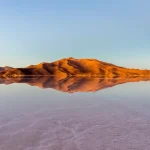 Reflejo infinito de montañas y cielo al amanecer en el Salar de Uyuni en Potosí, Bolivia