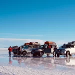 Vehículo todoterreno recorriendo la inmensidad blanca del Salar de Uyuni en Bolivia - Llamitas Travel